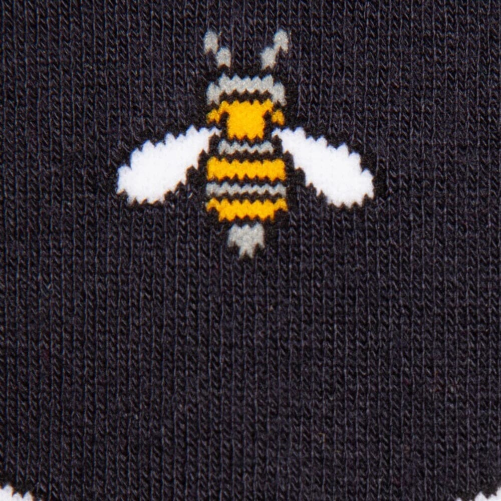 Close-up of a black knit sock featuring a knitted bumblebee design in yellow, black, and white.