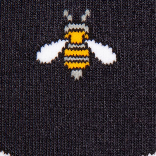 Close-up of a black knit sock featuring a knitted bumblebee design in yellow, black, and white.