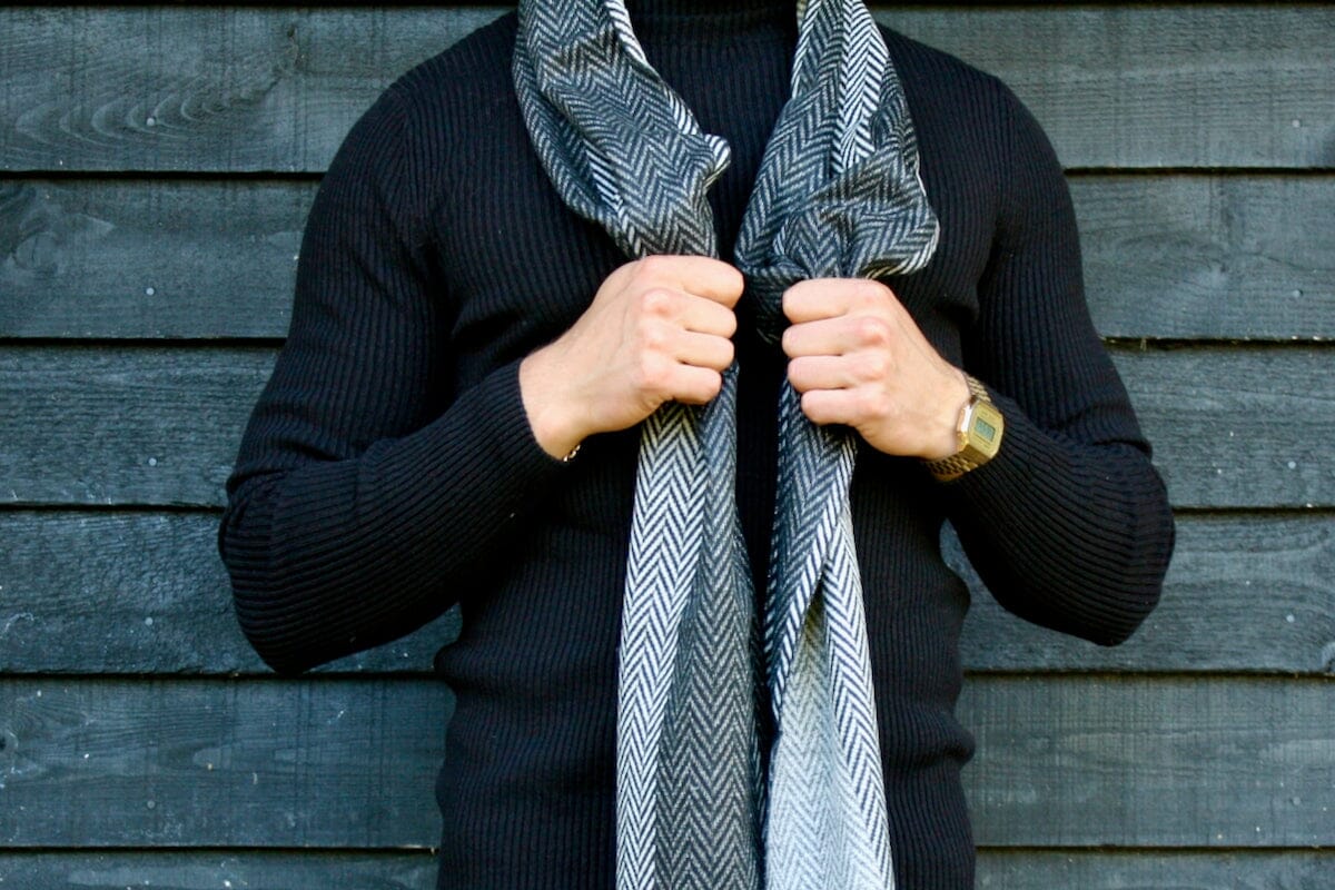 A man in a black jumper wearing a the black and white herringbone scarf
