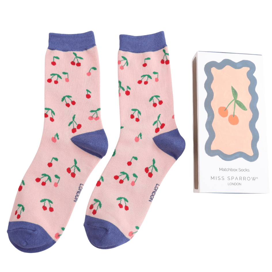 Pink socks with cherry pattern and blue accents, displayed with packaging on a white background.