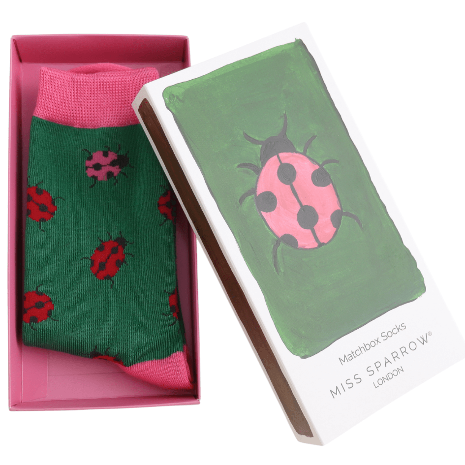 Green socks with ladybug pattern in a pink box, featuring 'Miss Sparrow' packaging.