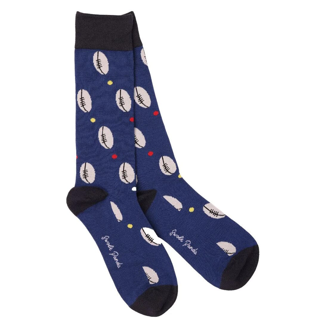 A pair of navy blue crew socks with a repeating pattern of white rugby balls and small colorful dots, featuring black heels, toes, and cuffs.