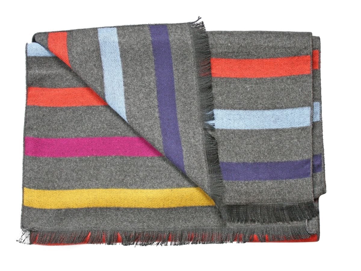 A grey scarf with tassled ends with stripes in yellow, pink, orange, blue and purple.